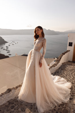 Ivory wedding dress with a fitted beaded bodice, sheer long sleeves, and a full flowing skirt with train