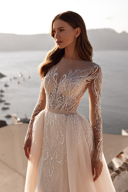Close-up of an ivory wedding dress with a high illusion neckline, sparkling floral beadwork, and sheer sleeves