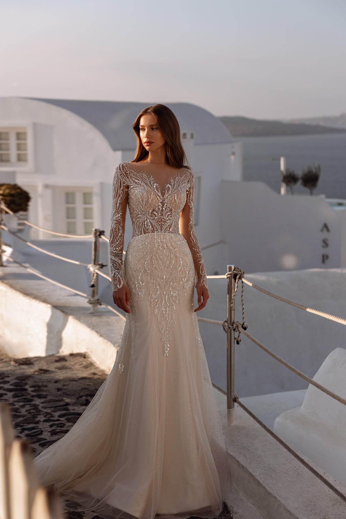 Fitted ivory wedding dress with a bateau neckline, sheer embellished sleeves, and a softly flared train