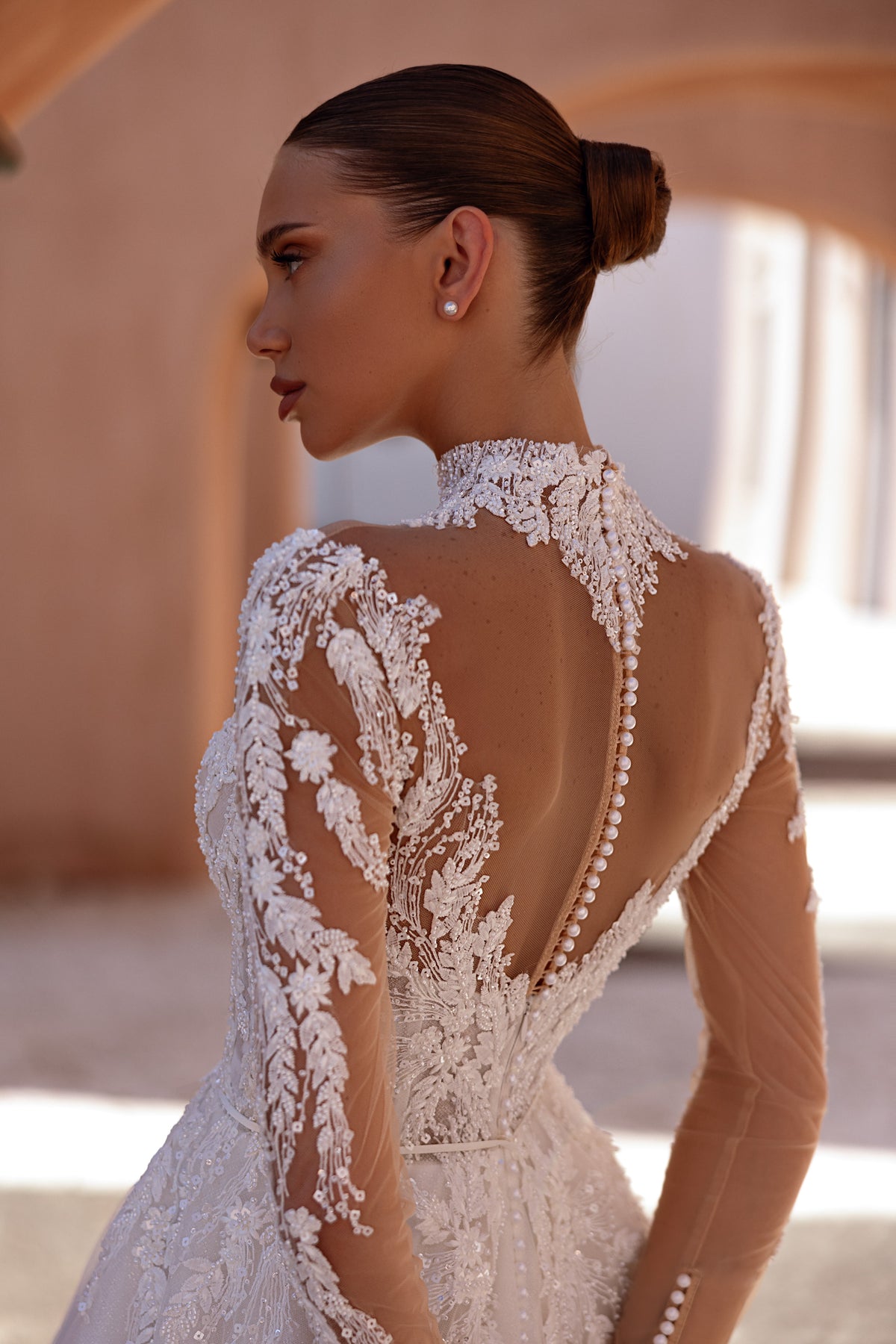 Sheer illusion back with covered buttons and lace sleeves on an ivory A-line wedding dress