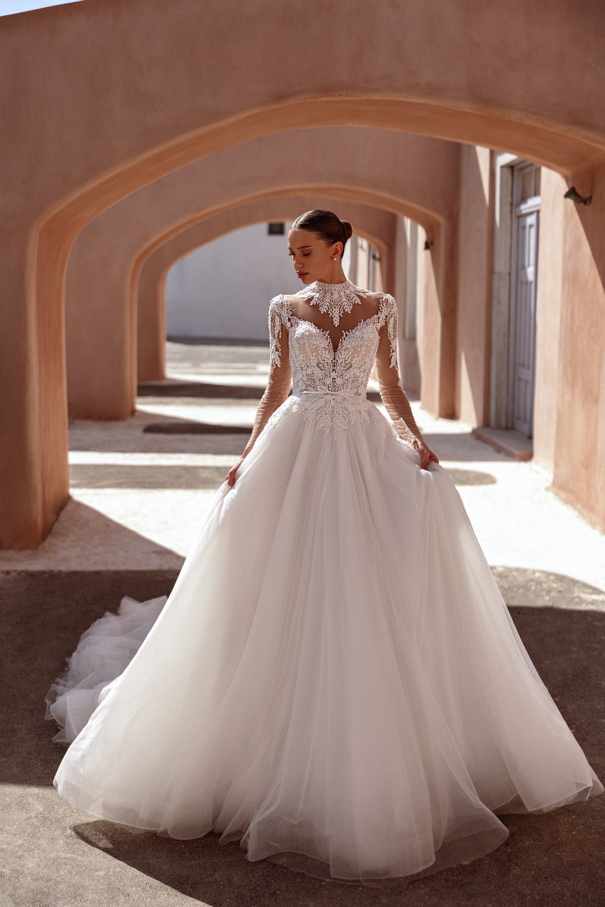 Full A-line wedding dress with a high lace neckline, sheer long sleeves, and a flowing tulle skirt