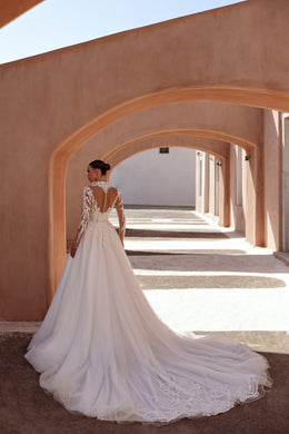 Ivory wedding dress showing a sheer lace back, button closure, long sleeves, and an extended train