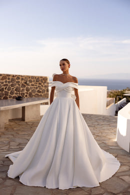 Ivory A-line wedding dress with a sculpted off-the-shoulder crossover neckline and full, floor-length skirt