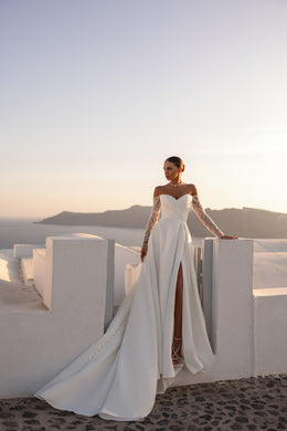 Ivory wedding dress with a long flowing train, off-the-shoulder lace sleeves, and a dramatic front slit