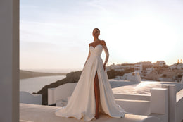 Full-length ivory wedding dress with a sweetheart neckline, sheer off-the-shoulder sleeves, high slit, and train