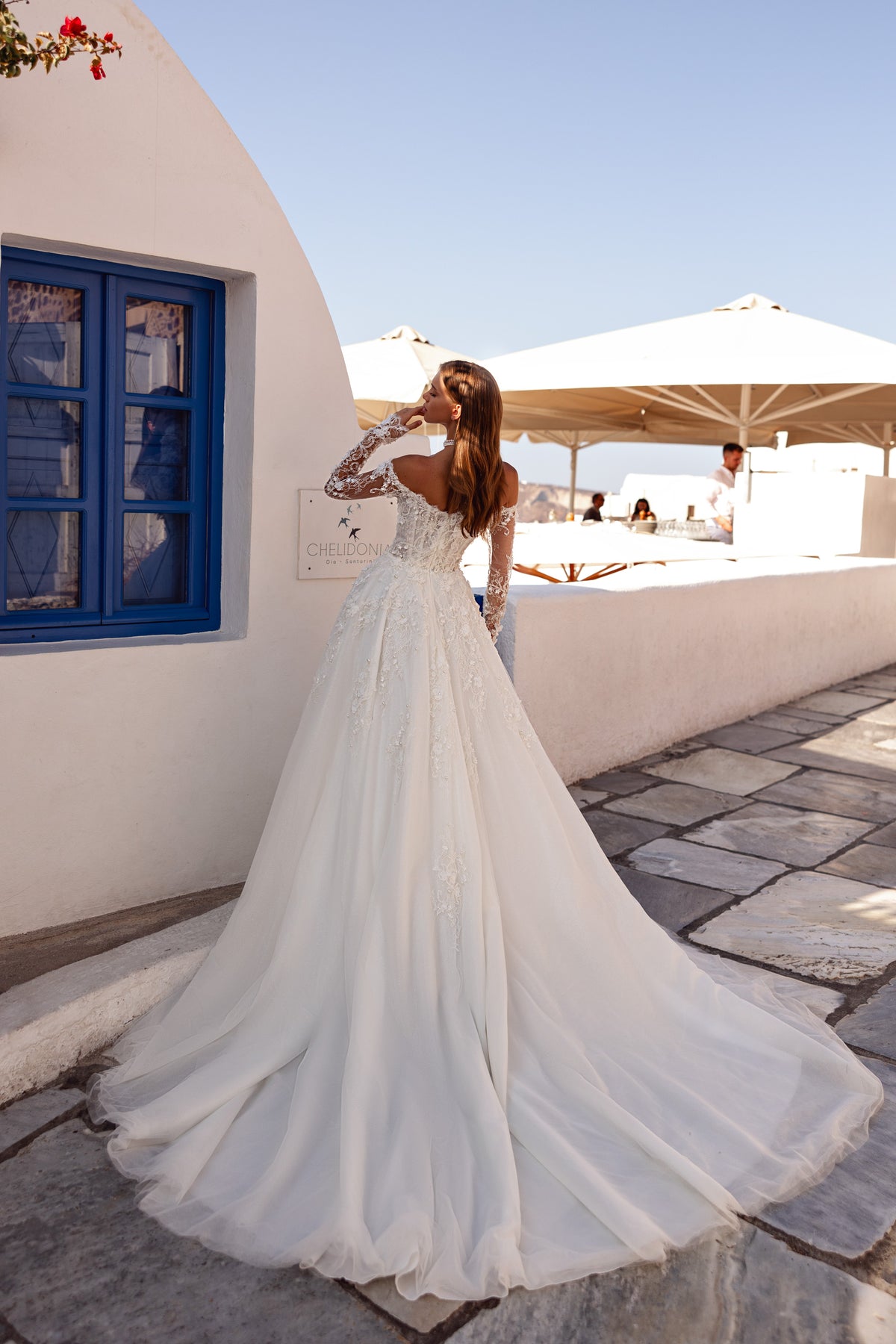 Back view of an ivory wedding dress with lace sleeves, a flowing skirt, and an extended train