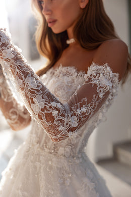 Close-up of floral lace sleeves and an off-the-shoulder bodice on an ivory wedding dress