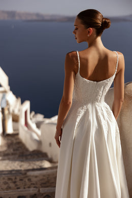 Ivory wedding dress featuring a low scoop back, slender straps, beaded lace bodice, and flowing skirt