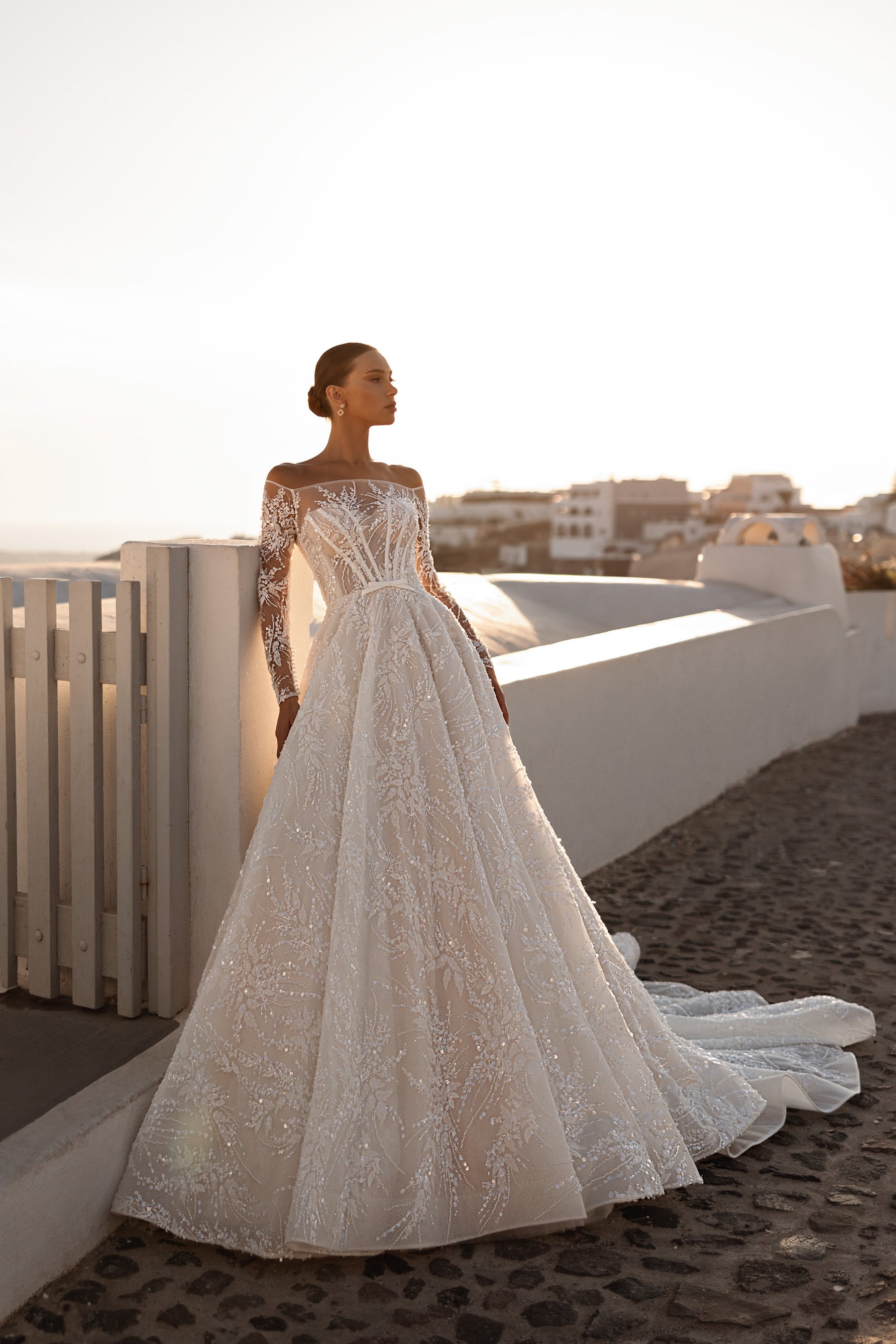 Ivory ball gown wedding dress with an off-shoulder neckline, lace sleeves, full glittering skirt, and train