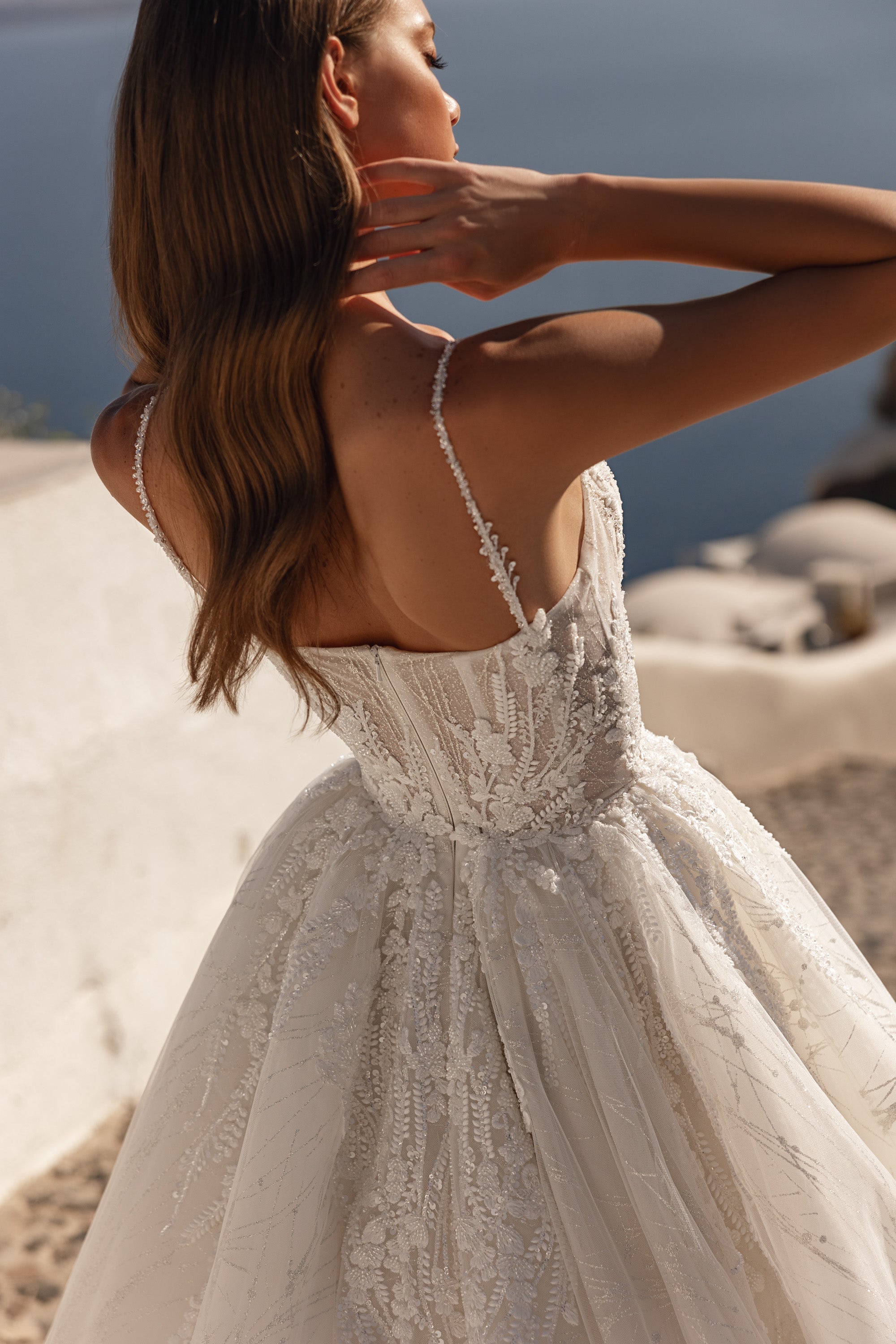 Open-back wedding dress with thin beaded straps, lace-covered bodice, and a flowing A-line skirt