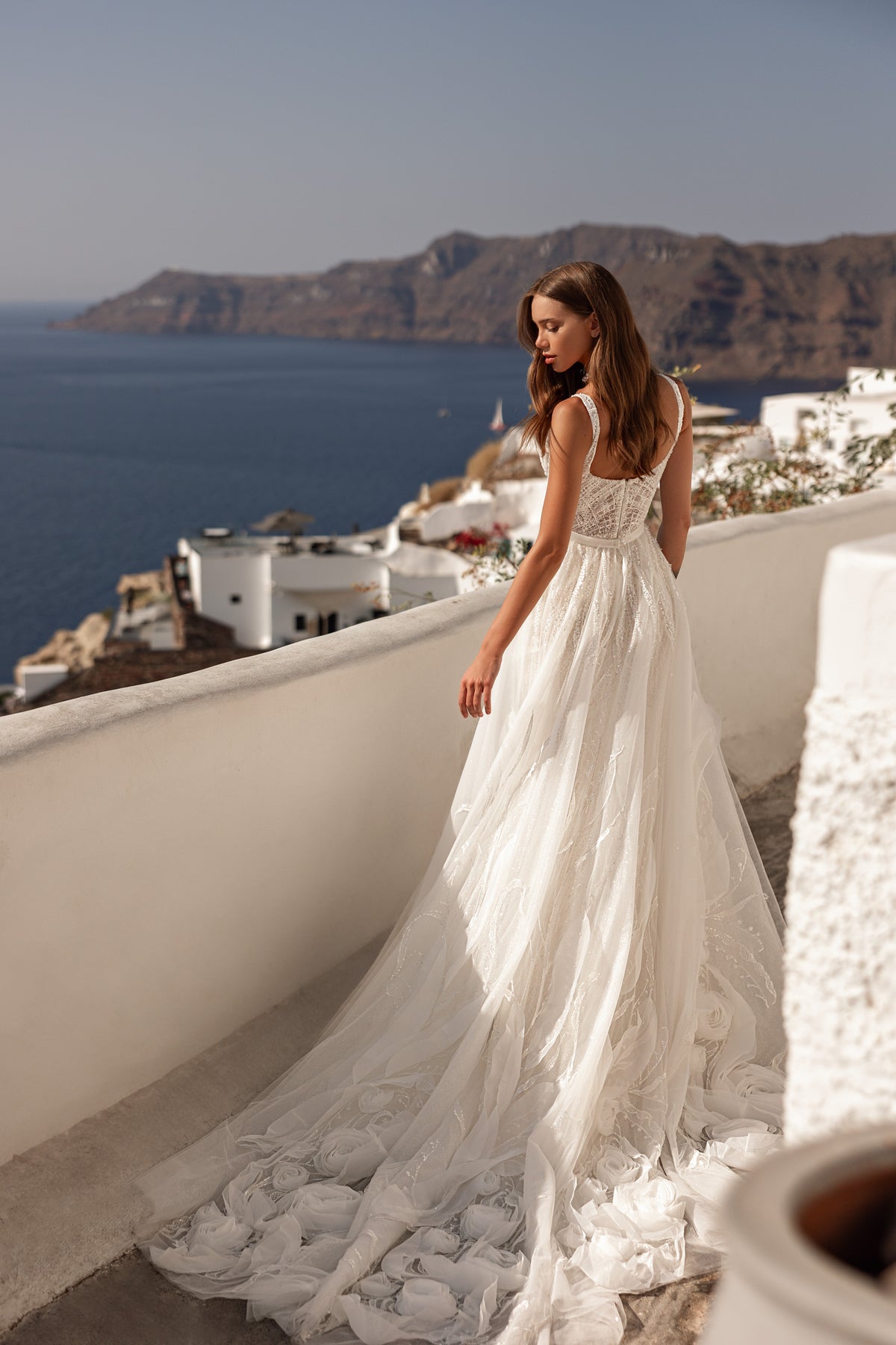 Ivory wedding dress with a lace bodice, flowing skirt, and extended train shown from the back