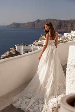 Ivory wedding dress with a lace bodice, flowing skirt, and extended train shown from the back