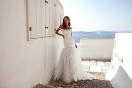 Ivory mermaid wedding dress featuring an off-the-shoulder neckline, fitted bodice, ruffled skirt, and train