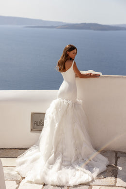 Open-back ivory mermaid wedding dress with a fitted bodice, ruffled skirt, and sweeping train