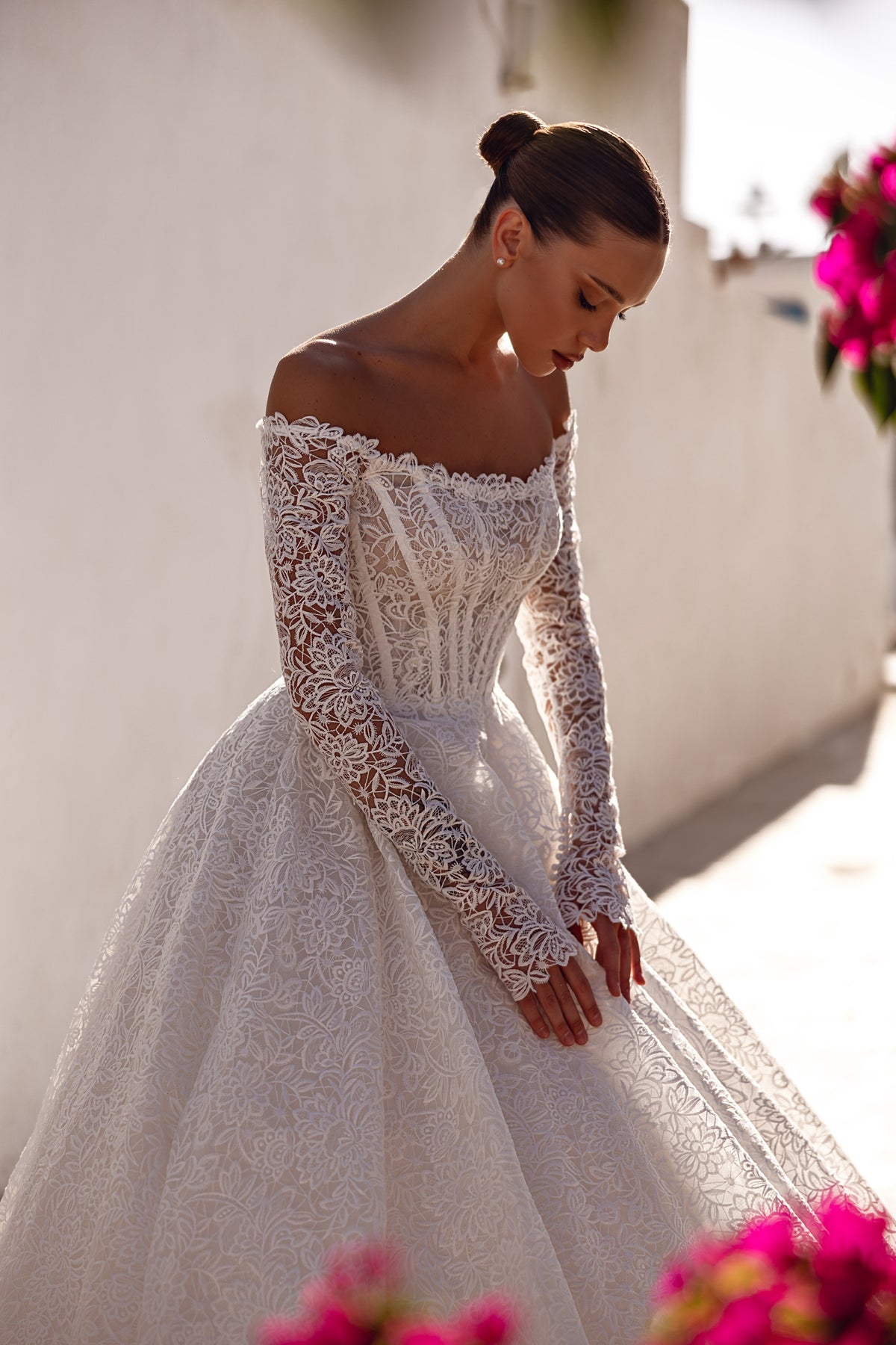 Detailed ivory lace wedding dress with an off-the-shoulder neckline, long sleeves, and full ball gown skirt