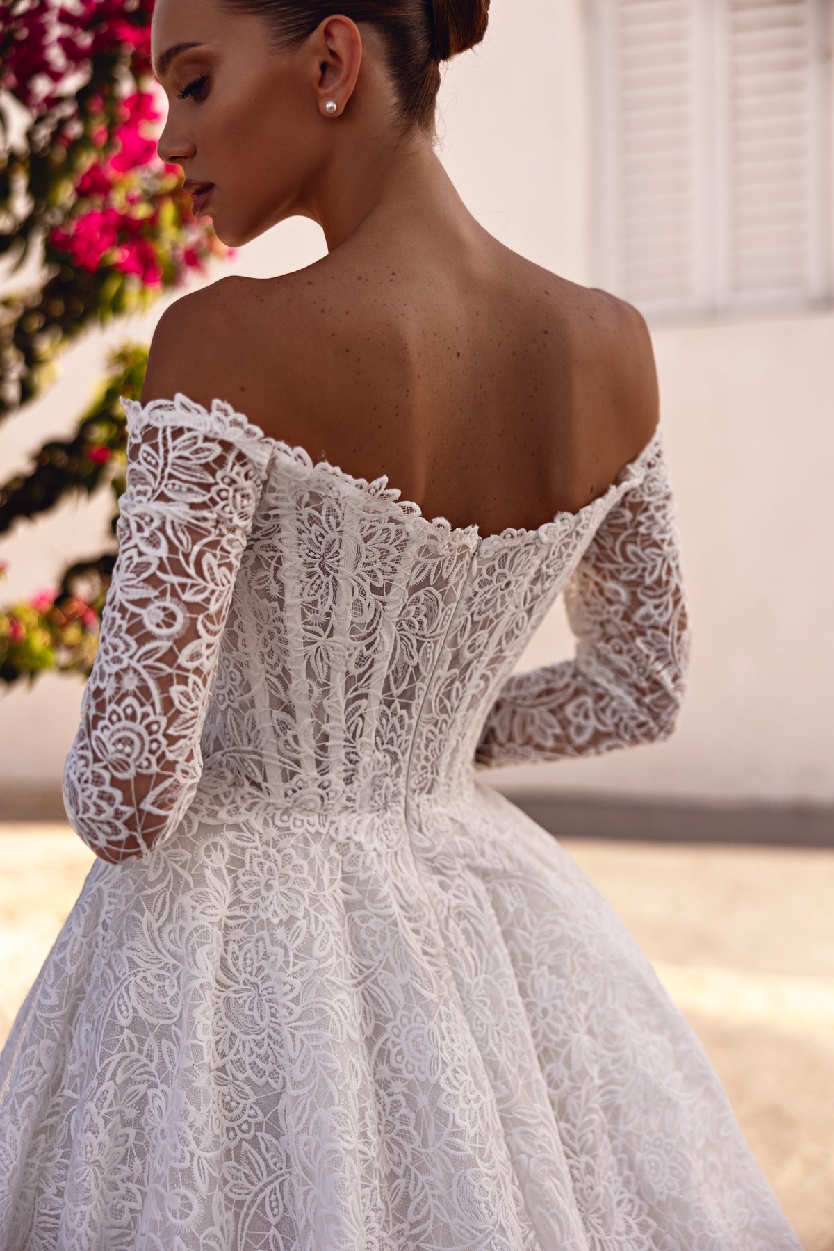 Open-back ivory lace wedding dress with an off-the-shoulder neckline, long sleeves, and full ball gown skirt