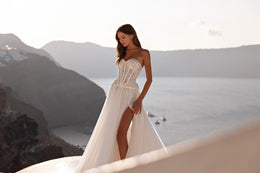Strapless ivory wedding dress featuring a lace corset, high slit, A-line skirt, and long train