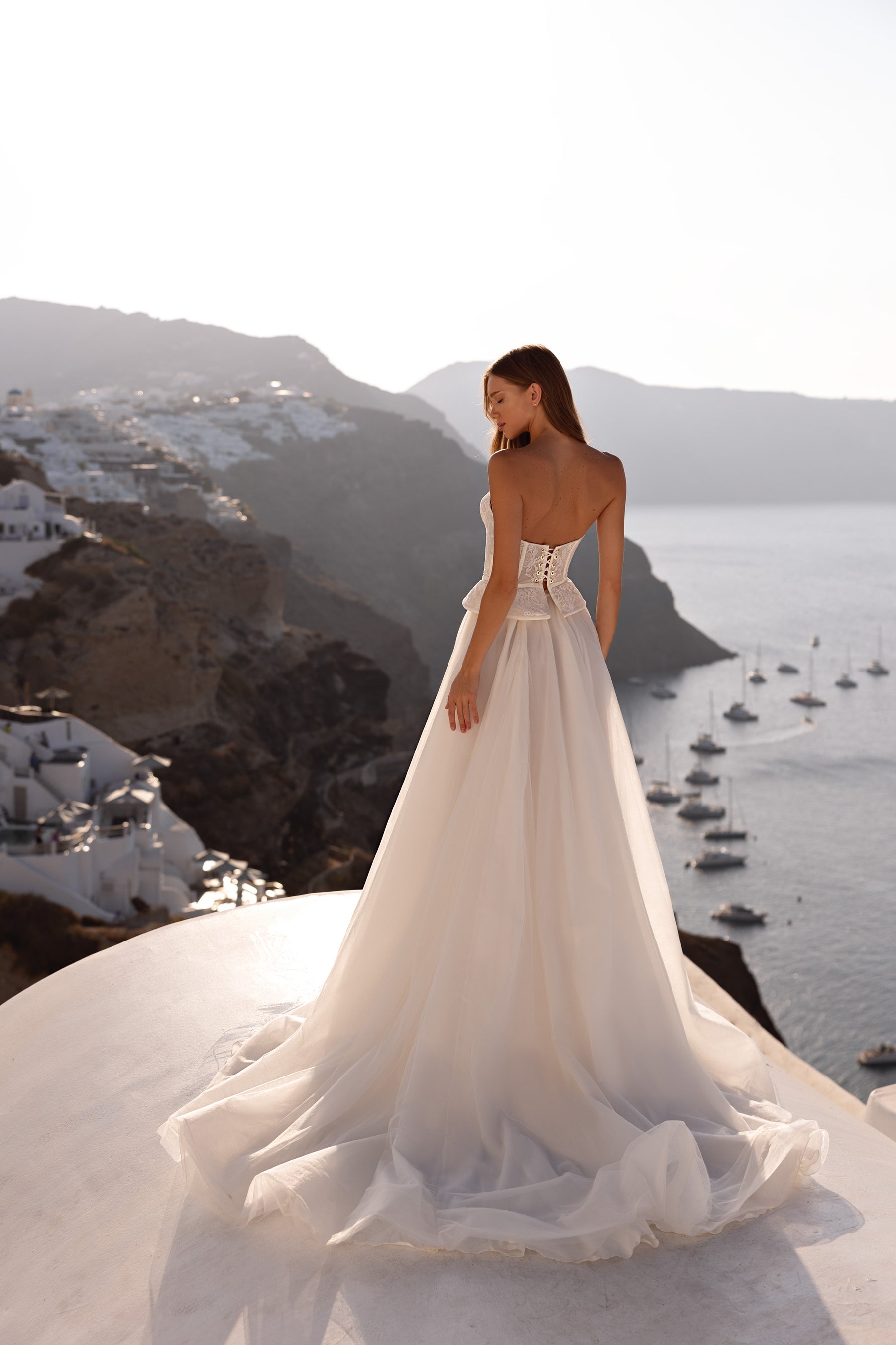 Back of an ivory wedding dress showing the lace corset closure, full skirt, and long trailing train