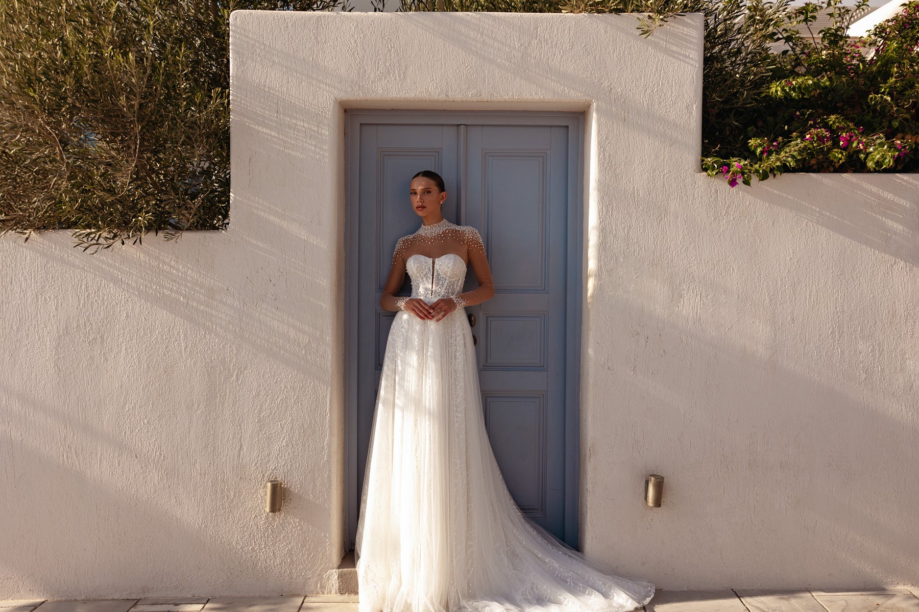 Ivory wedding dress featuring a sheer beaded neckline, long sleeves, A-line skirt, and extended train