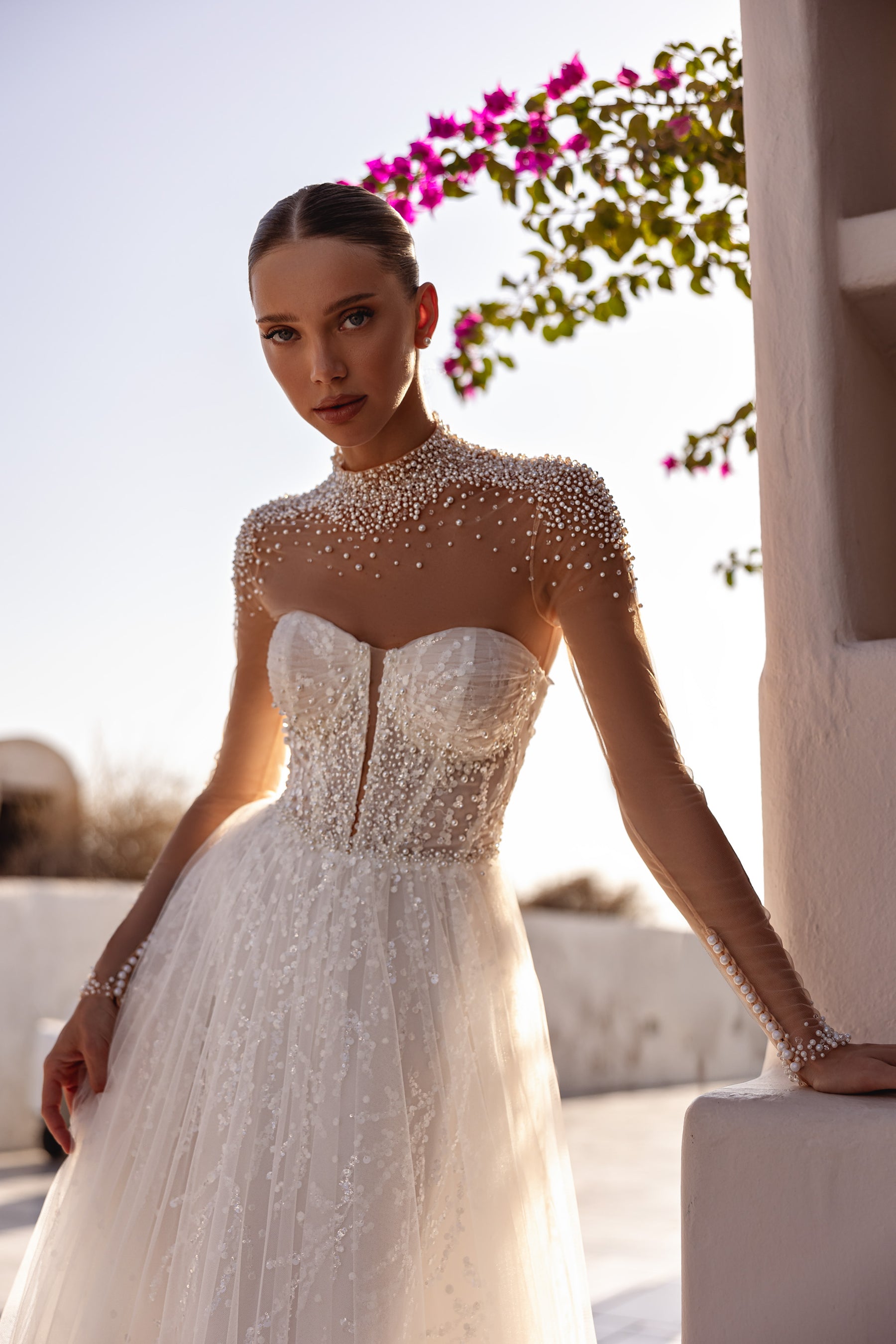 Close-up of pearl beading, sheer sleeves, and a sweetheart bodice on an ivory wedding dress