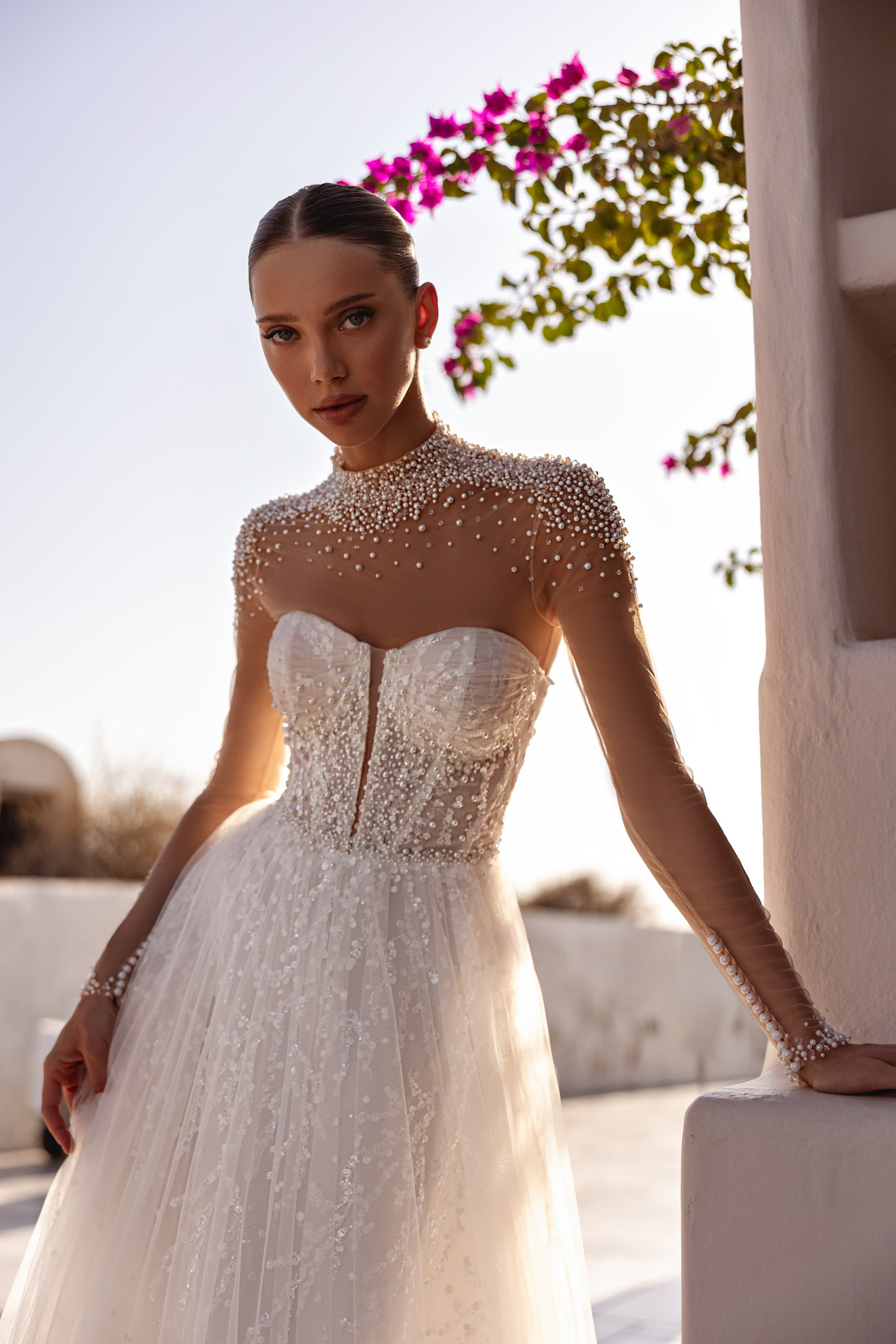 Close-up of pearl beading, sheer sleeves, and a sweetheart bodice on an ivory wedding dress