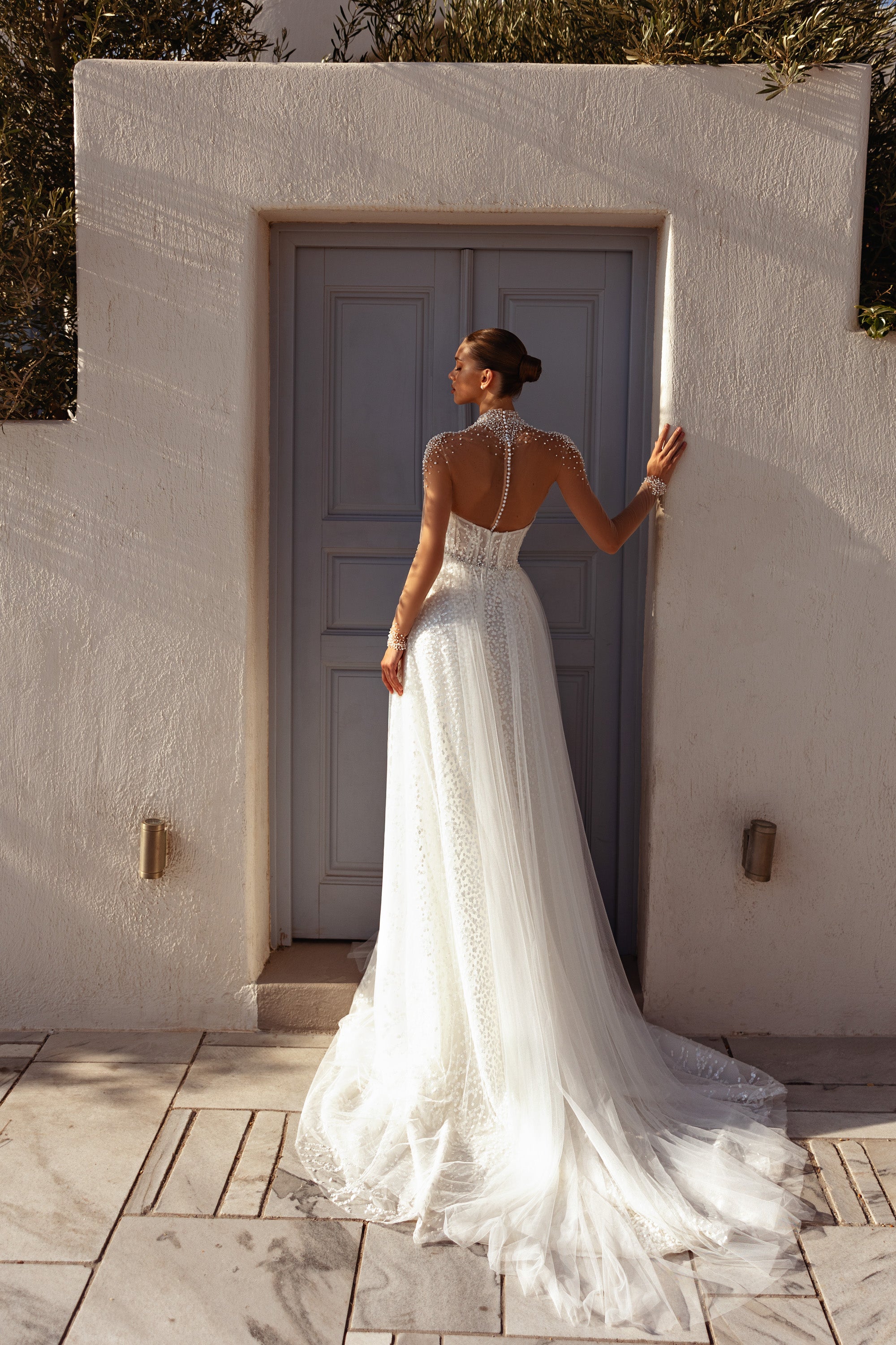 Open V-back wedding dress with a sheer beaded yoke, long sleeves, A-line skirt, and long train