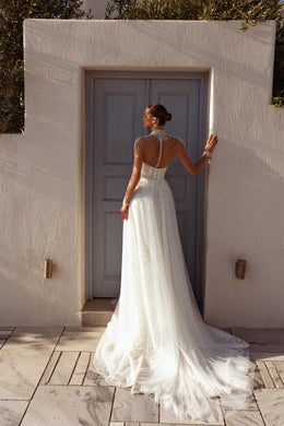 Open V-back wedding dress with a sheer beaded yoke, long sleeves, A-line skirt, and long train