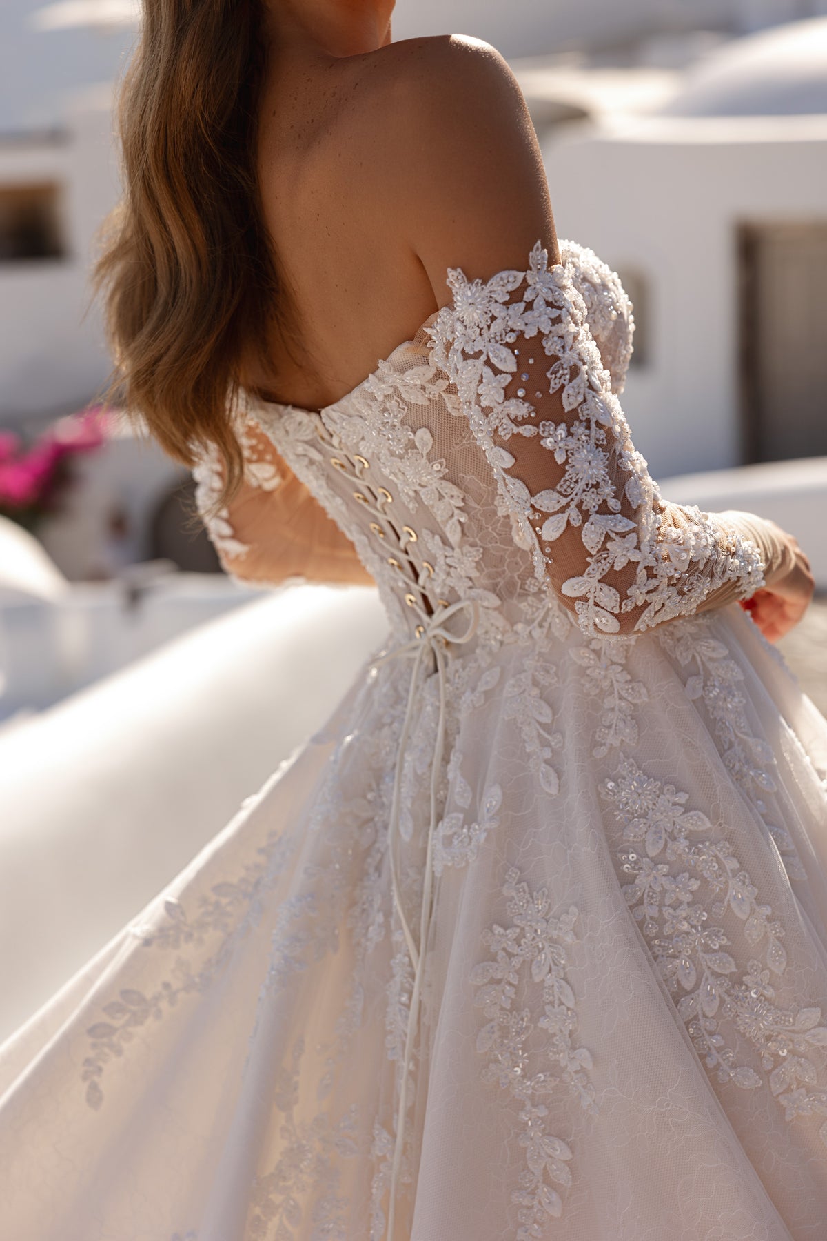 Close-up of the lace-up back, floral lace sleeves, and detailed appliqués on an ivory wedding dress