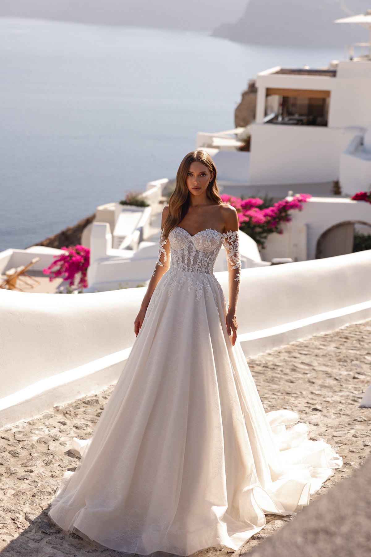 Ivory wedding dress with an embellished lace bodice, off-shoulder sleeves, and a wide flowing A-line skirt