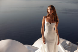 Fitted ivory wedding dress with a square neckline, slim straps, sculpted bodice, and long train