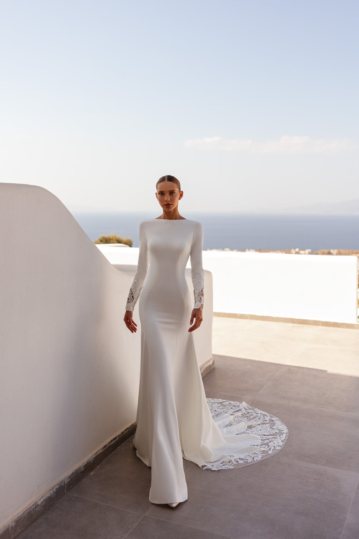 Ivory sheath wedding dress with a bateau neckline, long sleeves, and a lace-trimmed train