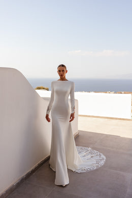 Ivory sheath wedding dress with a bateau neckline, long sleeves, and a lace-trimmed train