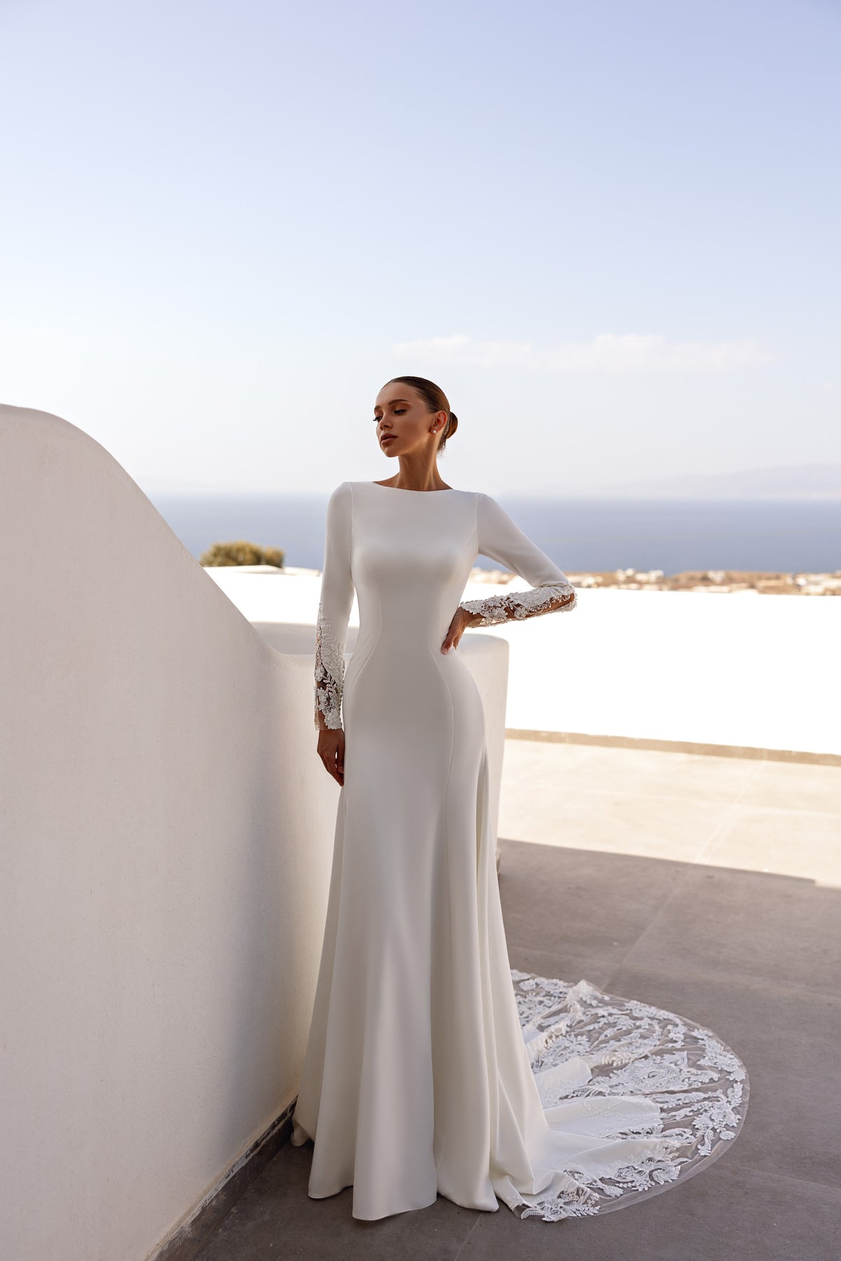 Ivory sheath wedding dress with long sleeves, a fitted silhouette, and a lace-edged train
