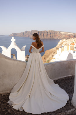 Ivory wedding dress showing an off-shoulder back, fitted waist, and sweeping floor-length train