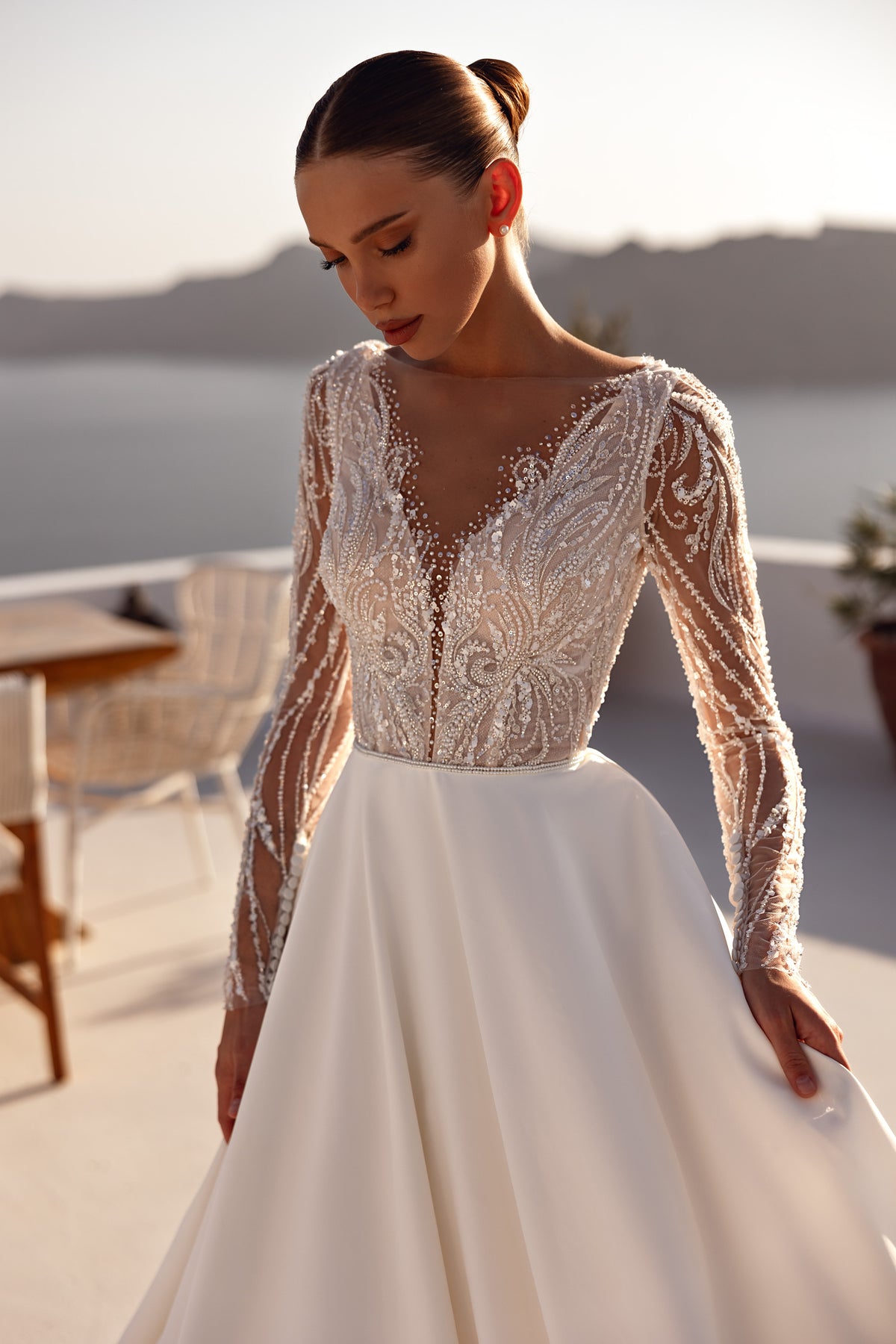 Close-up of a beaded illusion V-neck bodice and long sheer sleeves on an ivory wedding dress