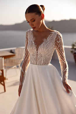 Close-up of a beaded illusion V-neck bodice and long sheer sleeves on an ivory wedding dress
