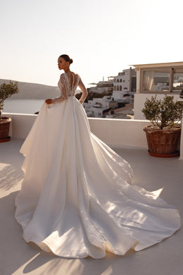 Sheer beaded back and flowing train on an ivory long-sleeve wedding dress
