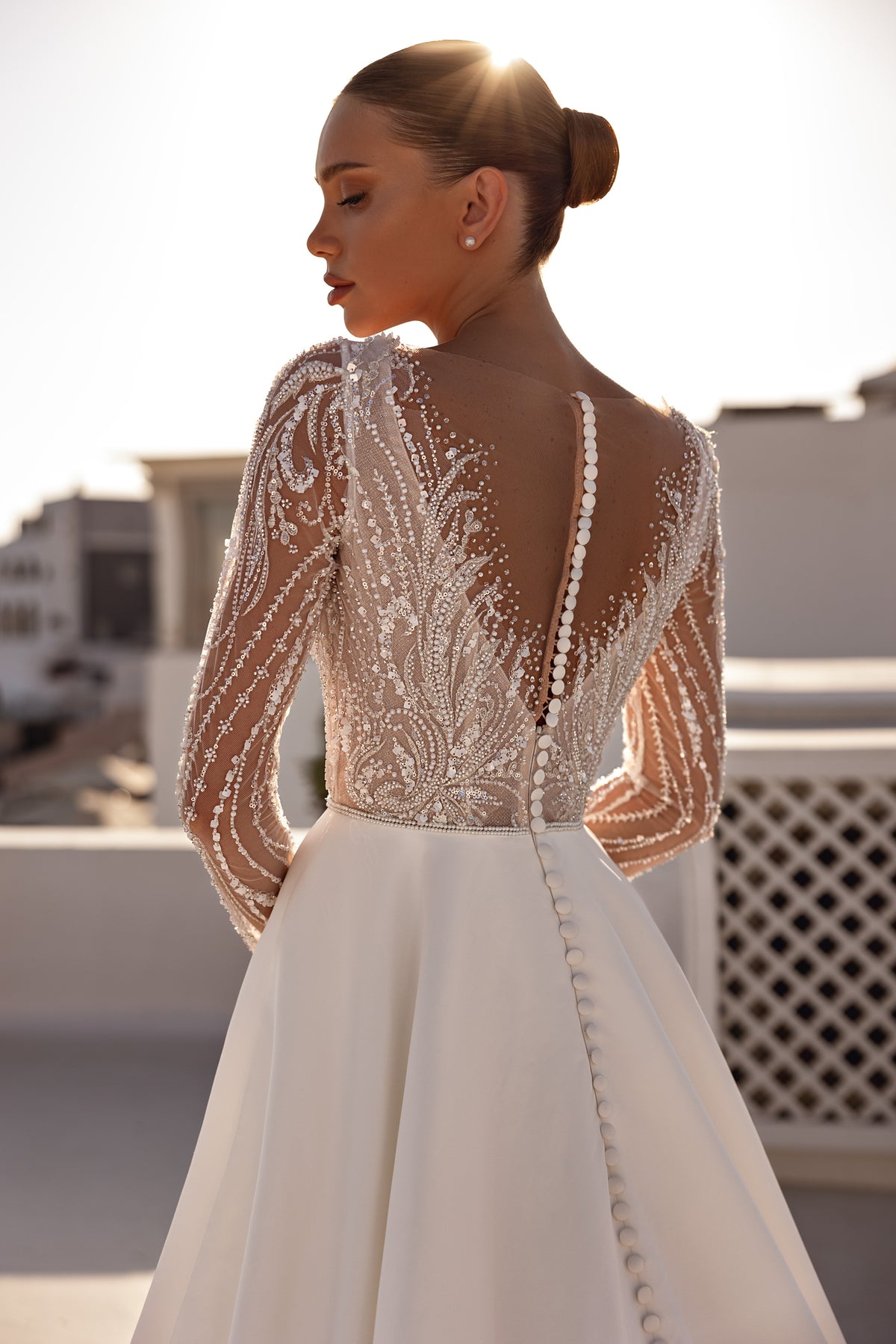 Sheer beaded back with covered buttons on the skirt of an ivory long-sleeve wedding dress