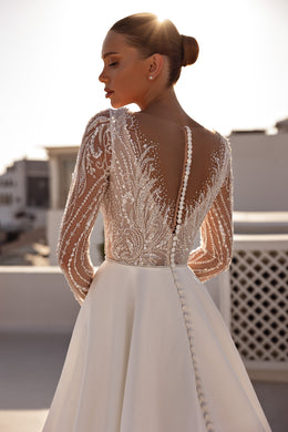 Sheer beaded back with covered buttons on the skirt of an ivory long-sleeve wedding dress