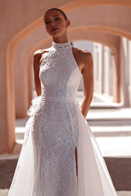 Close-up of floral lace and beadwork on the high-neck bodice of an ivory wedding dress with a side slit