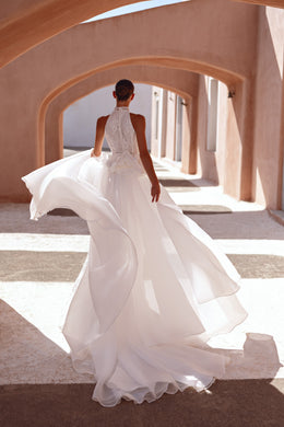 Lace-covered back and sweeping layered overskirt on an ivory high-neck wedding dress