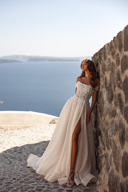 Ivory wedding dress with a sparkling embellished bodice, off-the-shoulder neckline, slit, and train