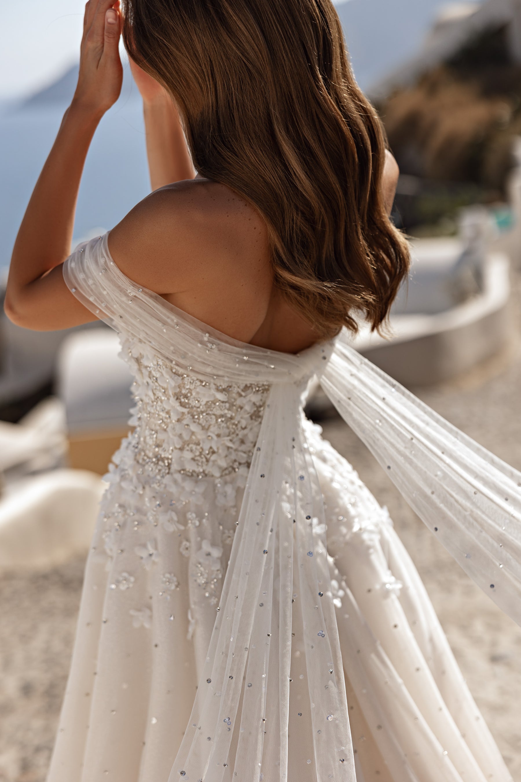 Embellished ivory wedding dress with an open back and draped off-the-shoulder sleeves