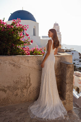 Sparkling ivory wedding dress with a fitted sheath silhouette and sheer trailing cape