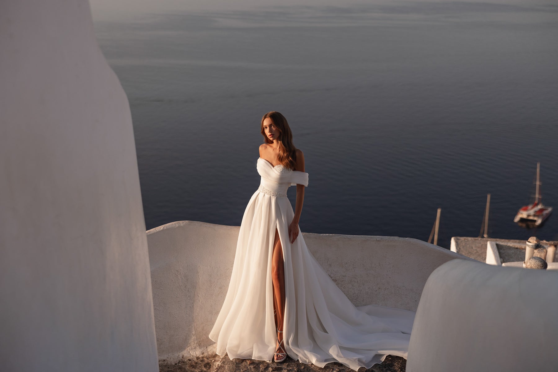 Ivory wedding dress featuring an off-the-shoulder bodice, sparkling waist detail, and thigh-high slit
