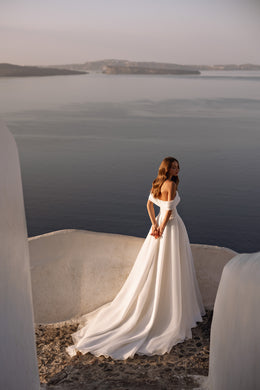 Ivory wedding dress with an off-the-shoulder neckline, full flowing skirt, and long train