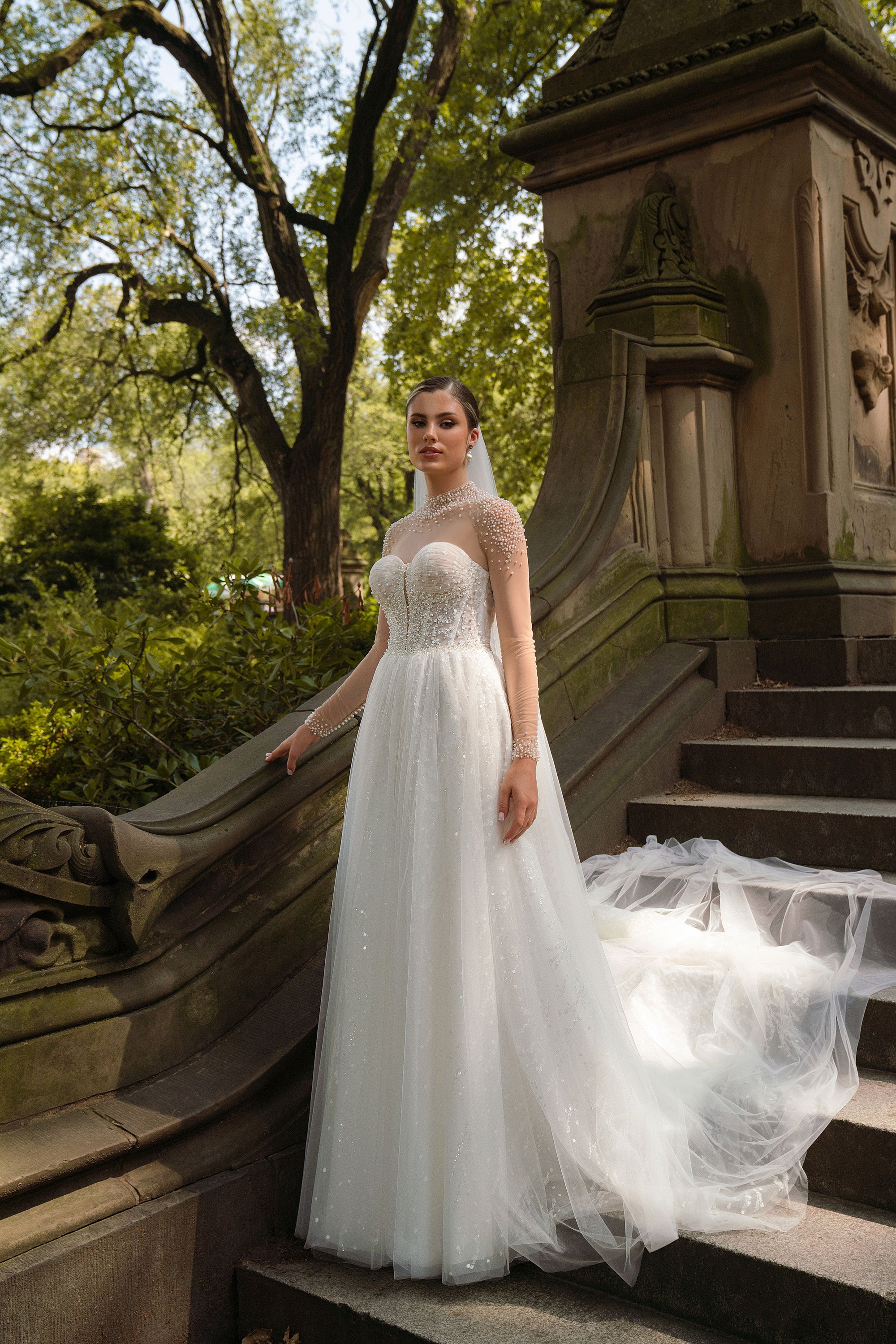 Ivory A-line wedding dress with a sweetheart bodice, pearl-embellished illusion neckline, and sheer long sleeves