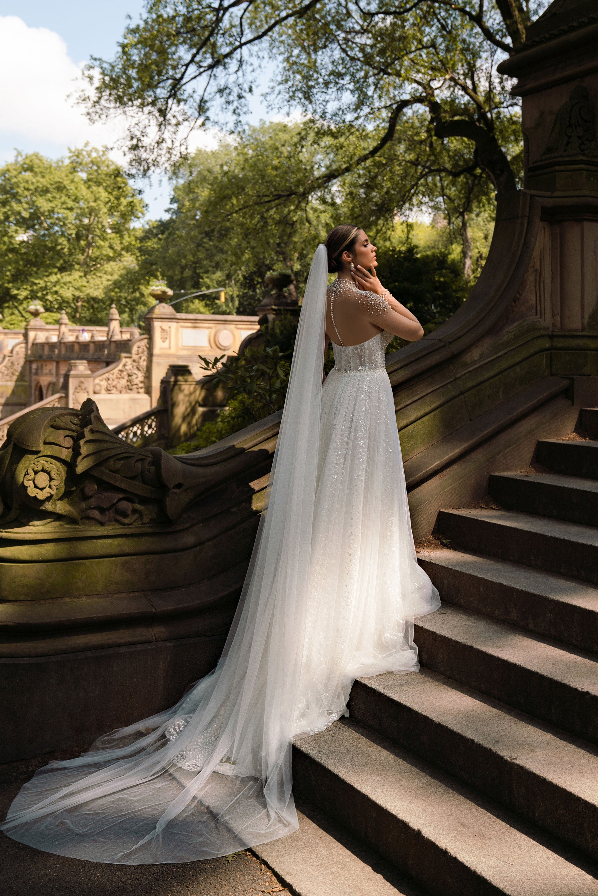 Sheer pearl-embellished back and long flowing train on an ivory A-line wedding dress
