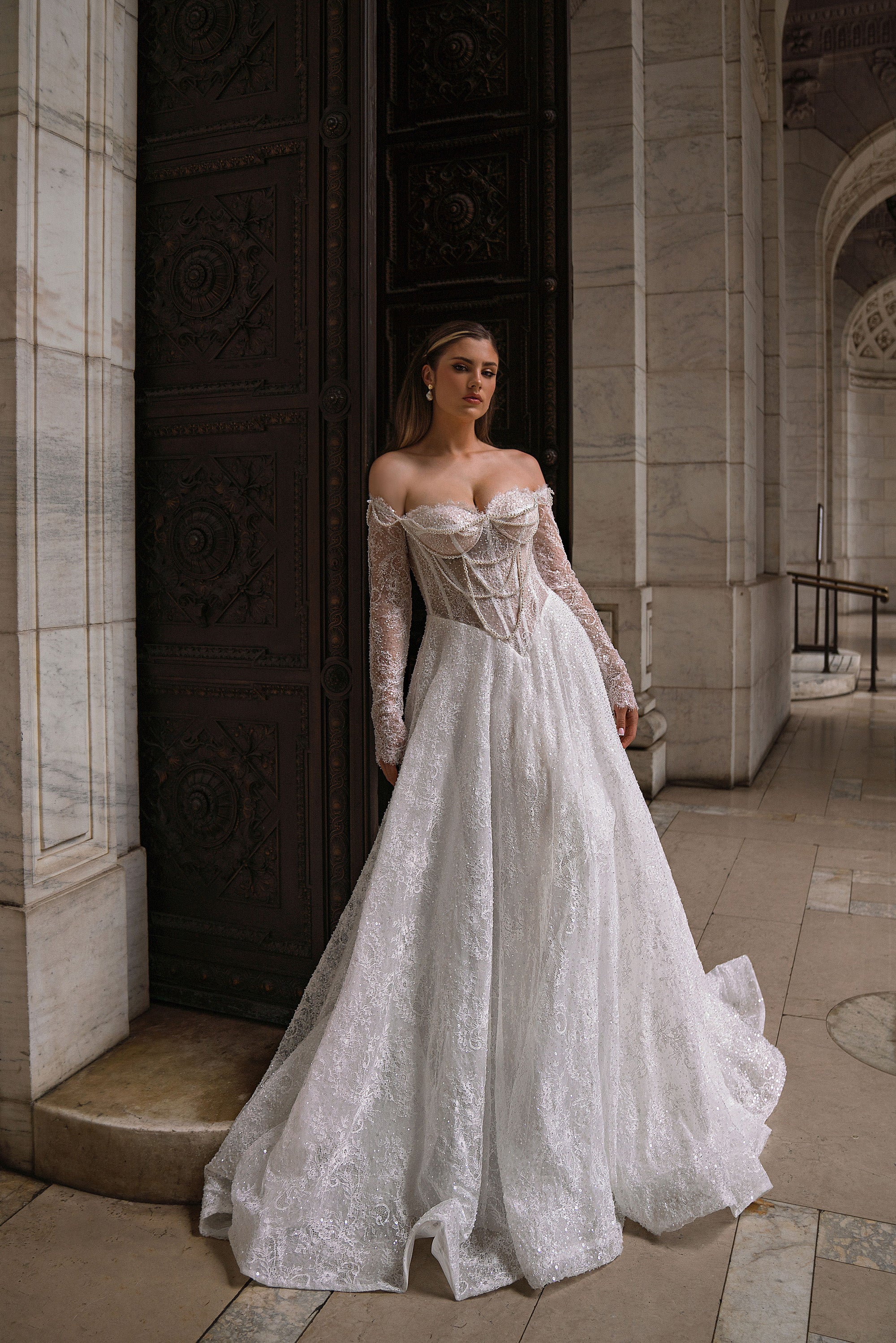 Ivory A-line wedding dress with an off-the-shoulder beaded lace bodice, long sleeves, and a sweeping train