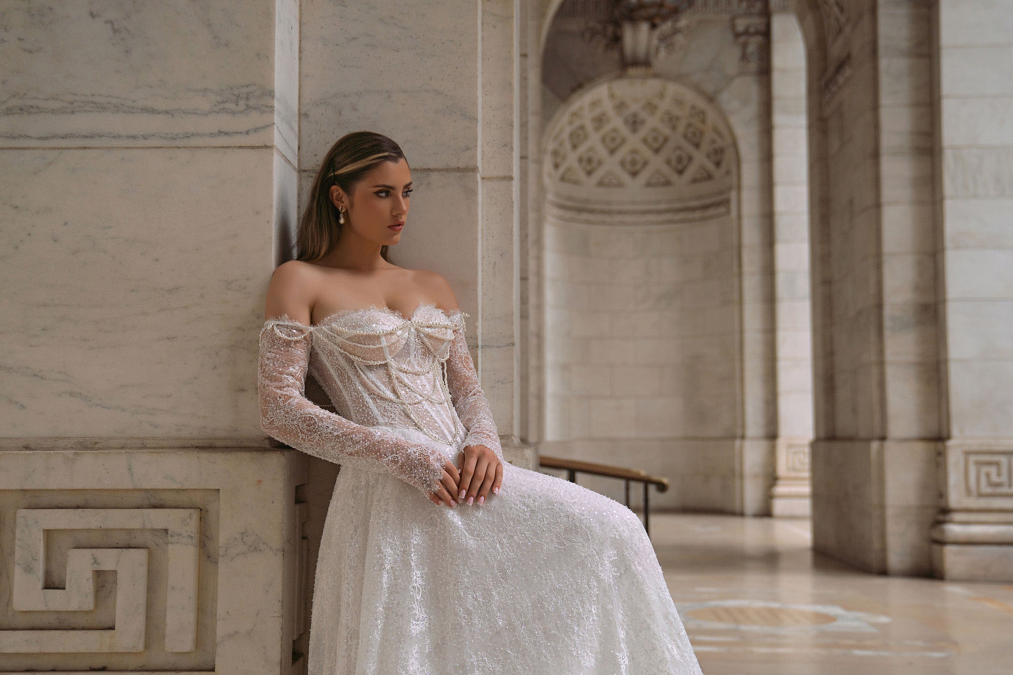 Beaded ivory wedding dress with an off-the-shoulder neckline, long sheer lace sleeves, and a flowing full skirt